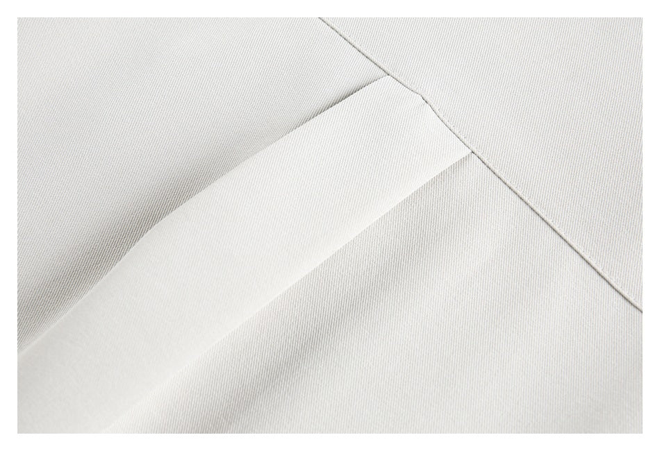 Close-up of an overlapping light ivory garment panel and stitched seams.