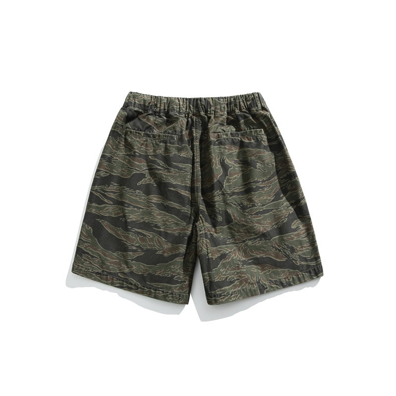 Back view of dark green and brown camouflage shorts with an elastic waistband and two rear pockets, on white.