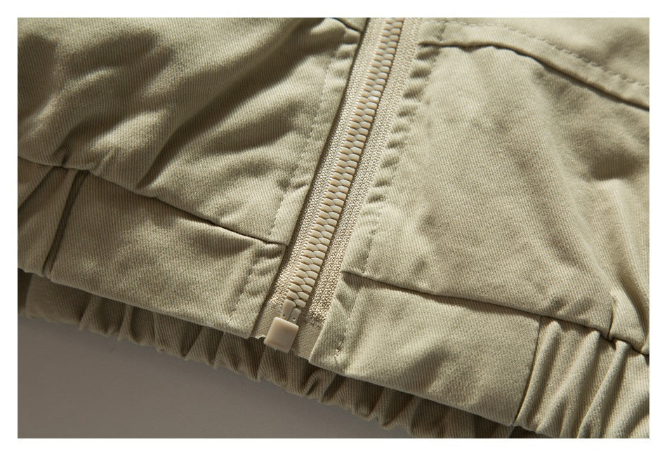 Close-up of a beige garment's zipper, stitched panels, and gathered elastic hem.
