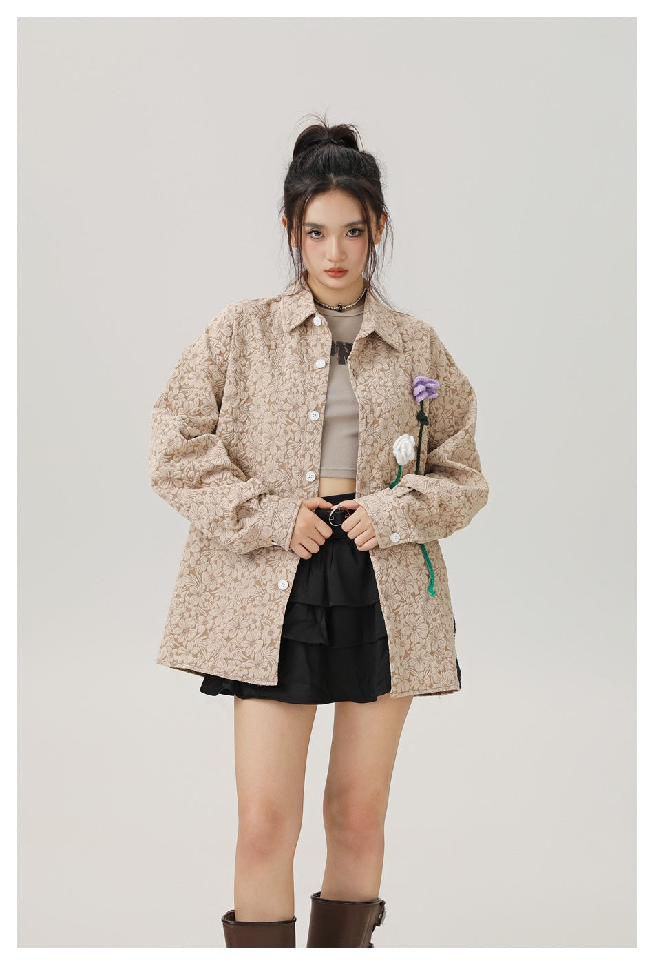 Model wearing a beige floral jacket with white buttons and purple and white flower appliqués.