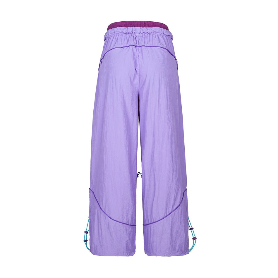 Back view of lavender purple wide-leg pants with piping seams, gathered waistband and turquoise hem cords