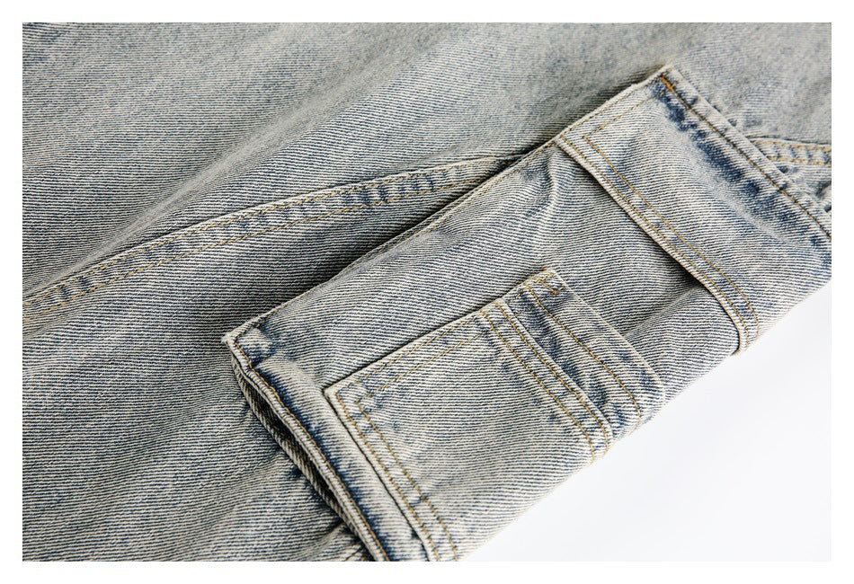 Close-up of a light-wash denim pocket flap and stitched pocket on a white background.