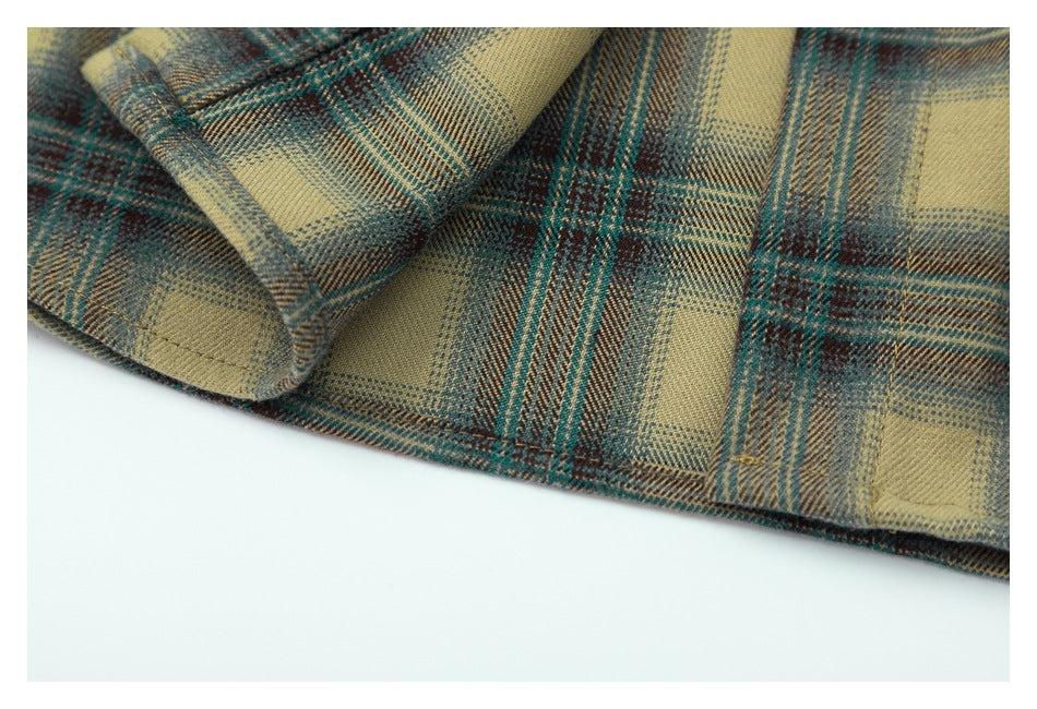 Close-up of the plaid shirt hem and folded fabric edge in tan, teal, and brown.