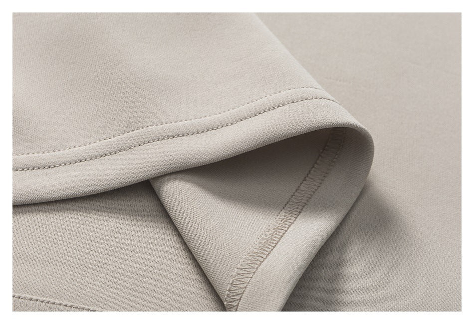 Close-up of a light beige garment hem folded back to show its stitching and overlocked inner seam.