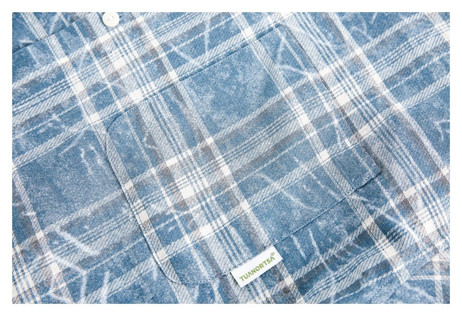 Close-up of a chest pocket on the blue-and-white plaid shirt, with a small sewn label.