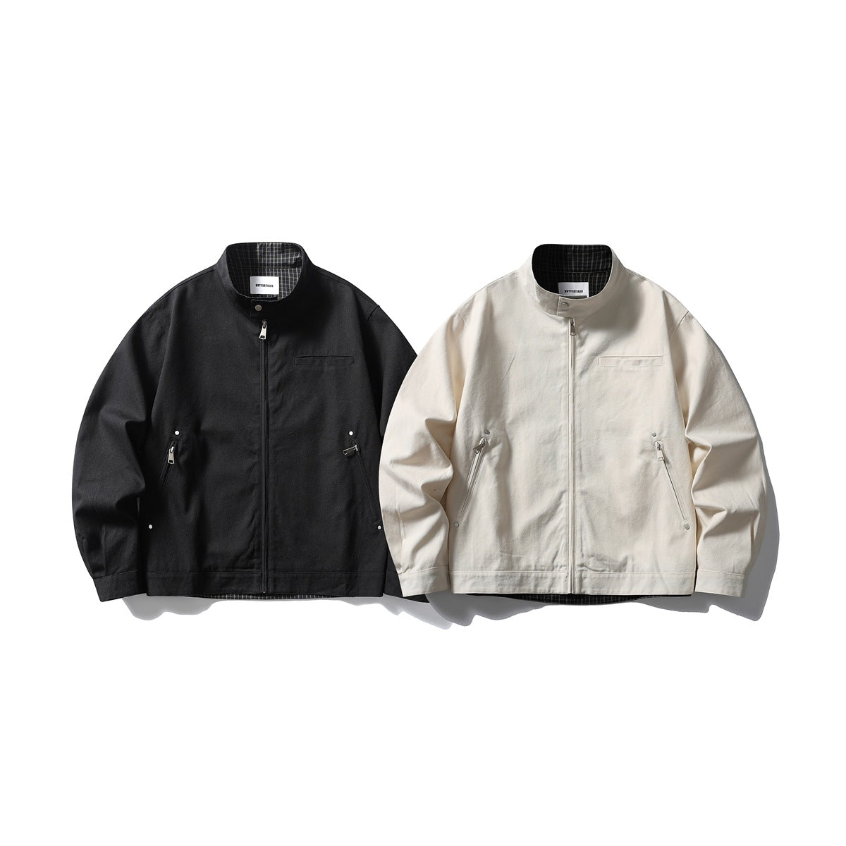 Front view of black and ivory stand-collar jackets with zippers, angled pockets, and plaid lining.
