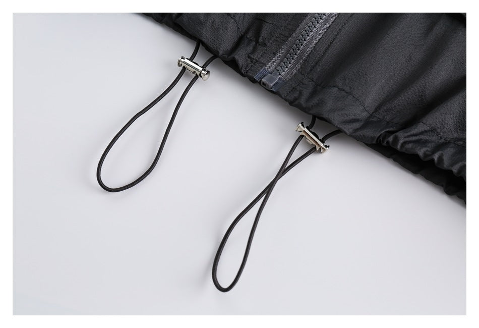 Close-up of the black jacket hem with two hanging drawcord loops and metal adjusters.