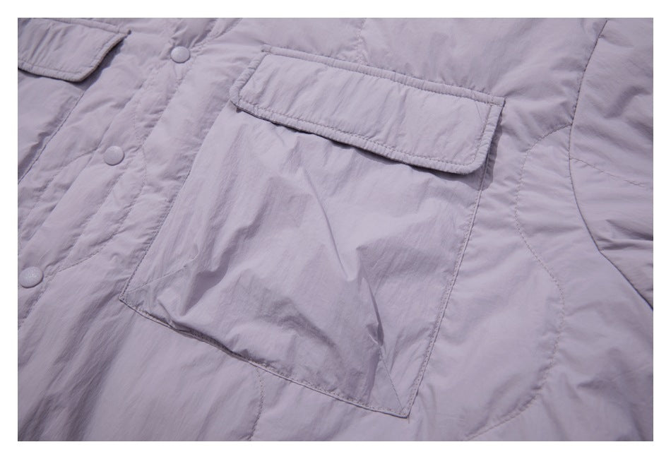 Close-up of a large flap chest pocket, snap buttons and curved quilting on the lavender jacket.