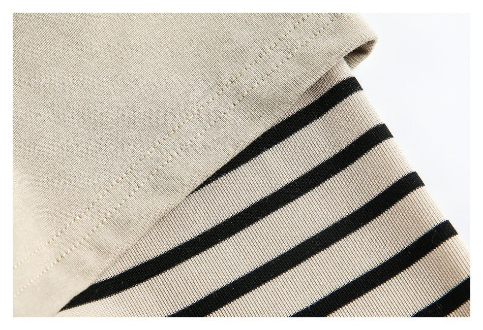 Close-up of beige fabric with black stripes and a double-stitched seam.