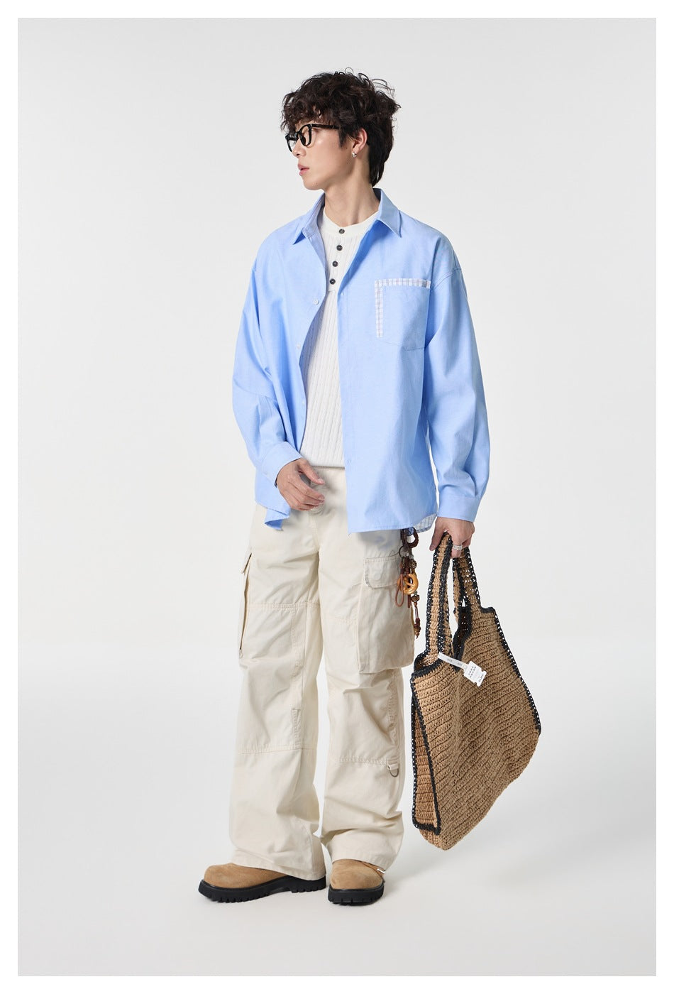 Model wearing a light blue button-up shirt with a plaid-trimmed chest pocket and cream cargo pants.