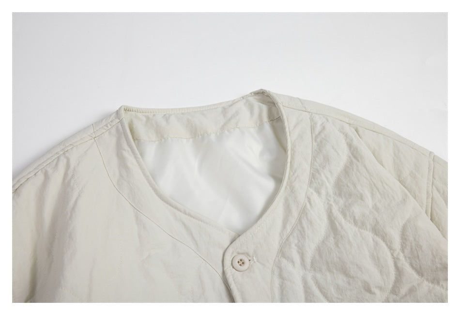 Close-up of the ivory jacket's rounded neckline, shoulder seams, quilted sleeve, and a front button.