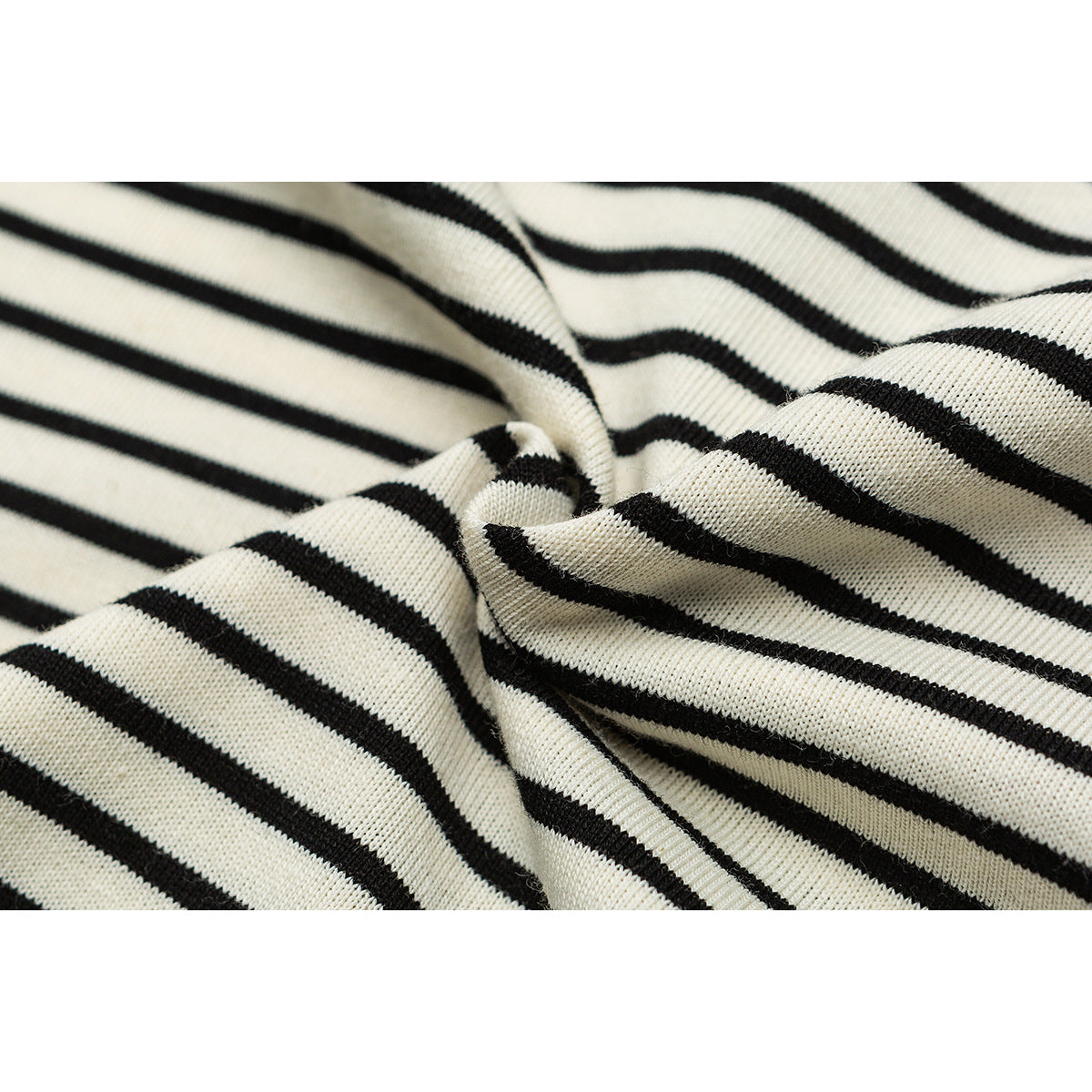 Macro view of cream knit fabric with narrow black stripes, gathered into folds.
