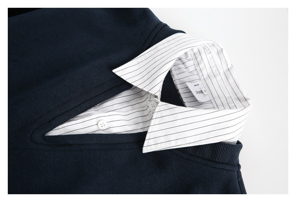 Close-up of the sweater neckline layered over a white, thinly striped shirt collar and placket.
