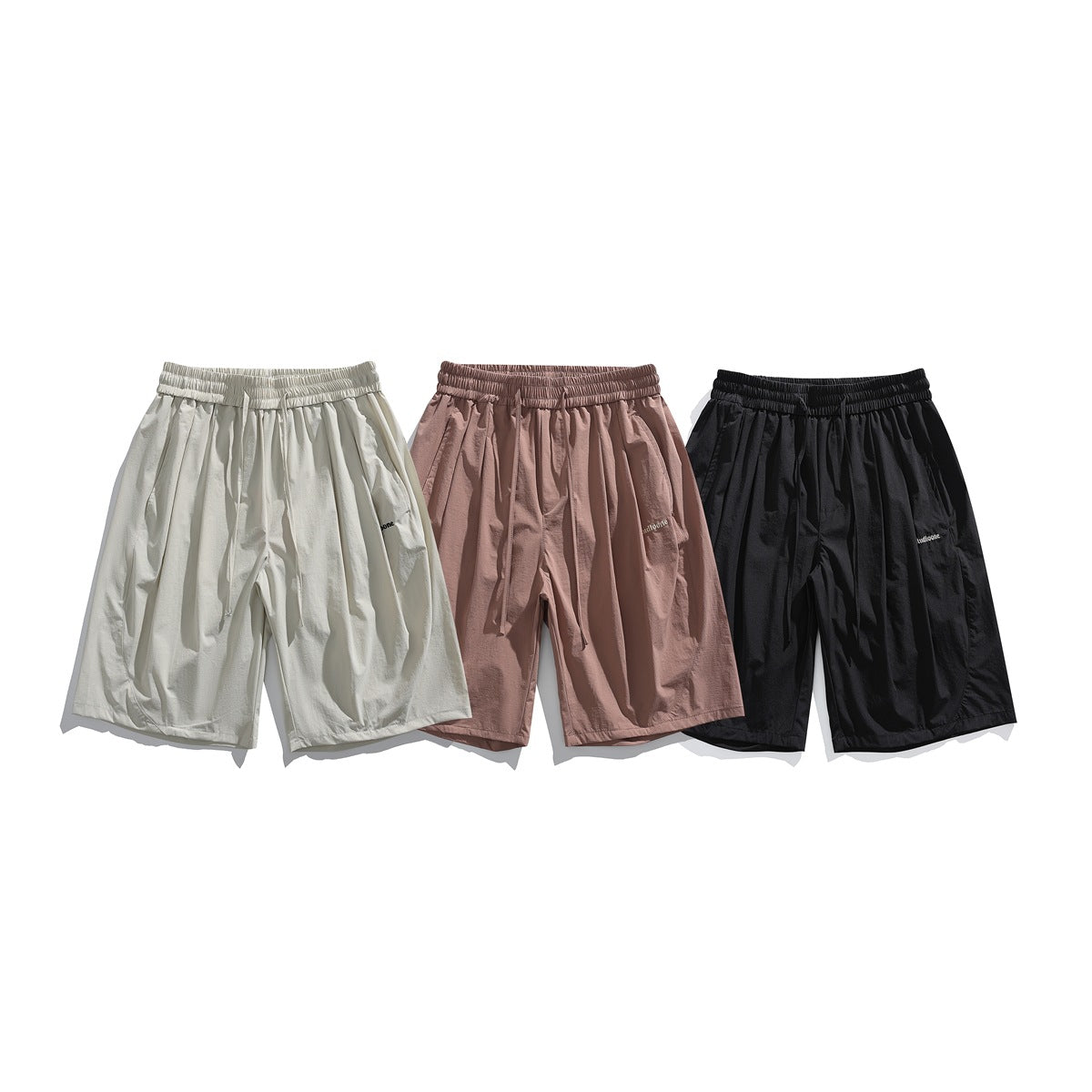 Three pairs of loose elastic-waist shorts shown from the front in light beige, dusty rose, and black.