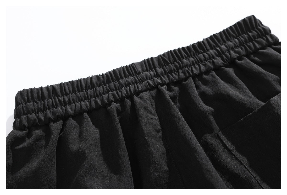 Close-up of black pants showing a gathered elastic waistband and stitched seams.
