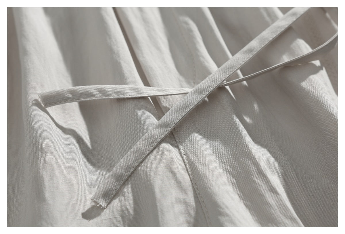 Close-up of cream garment fabric with two narrow ties crossing over it.