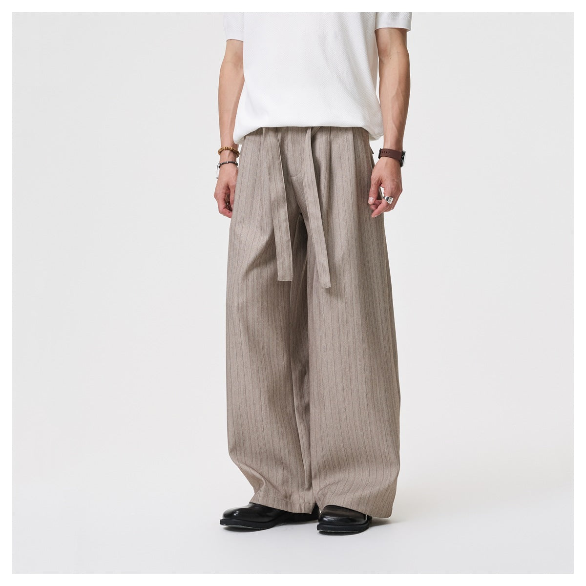 Model wearing khaki pinstriped wide-leg trousers with tie belt, white short-sleeve top and black leather shoes, front view
