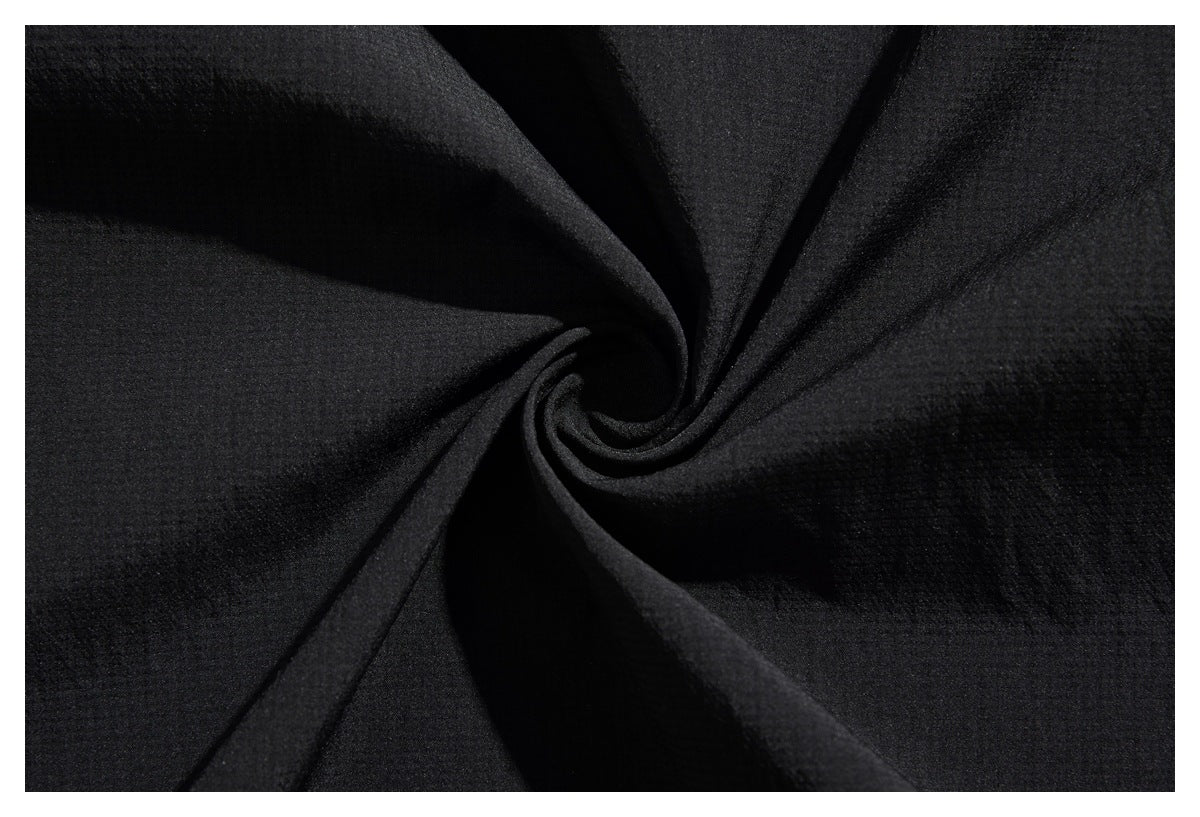Close-up of black fabric gathered into a spiral, showing its subtle textured surface.