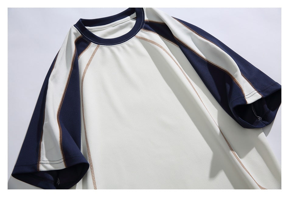 Close view of the ivory shirt front, showing navy raglan sleeves, a navy crew neck, and contrasting seam stitching.