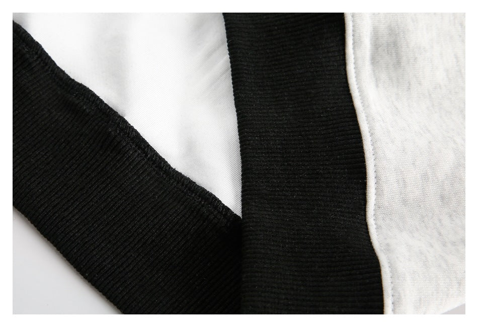 Close-up of black ribbed trim and stitching joined to light gray heather fabric.