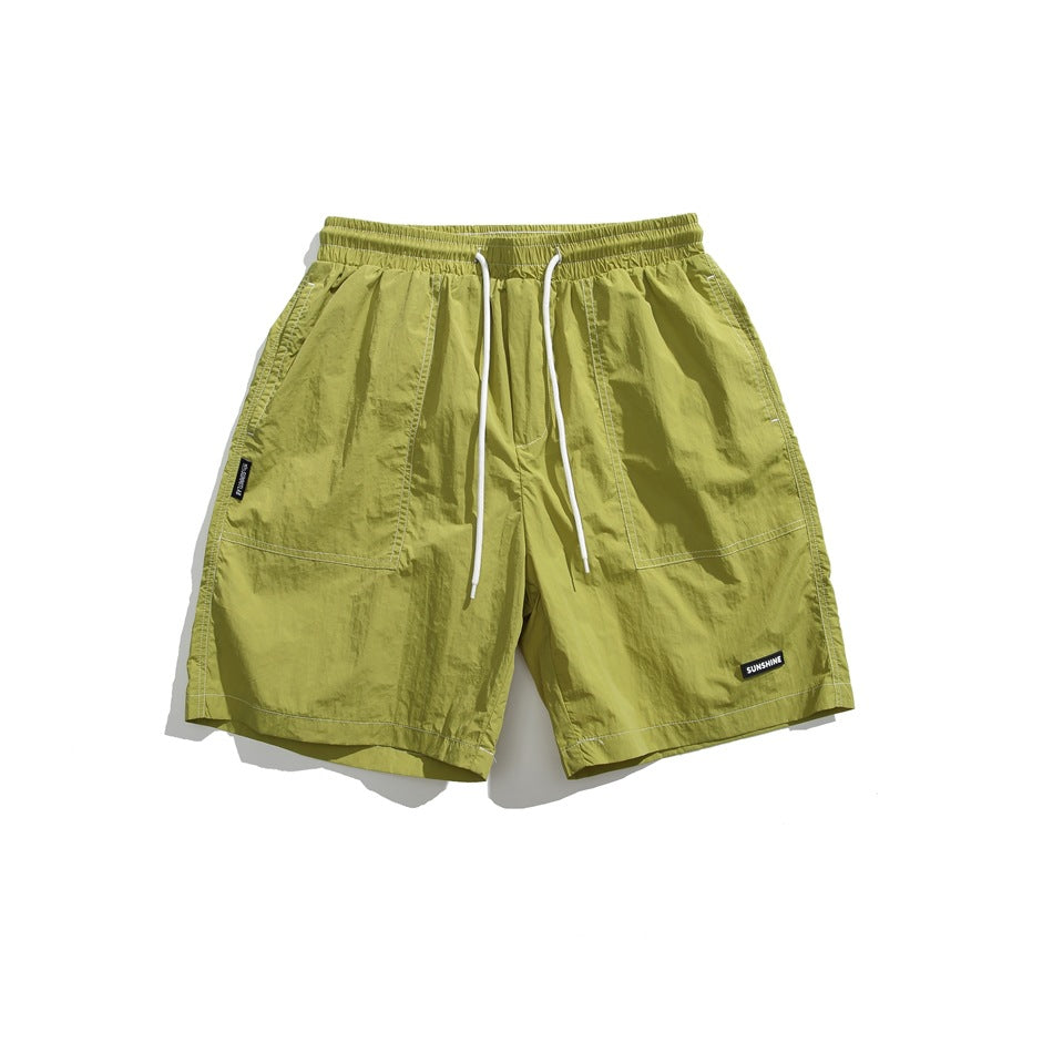 Front view of lime-green shorts with an elastic drawstring waist, two front pockets, and small sewn labels.