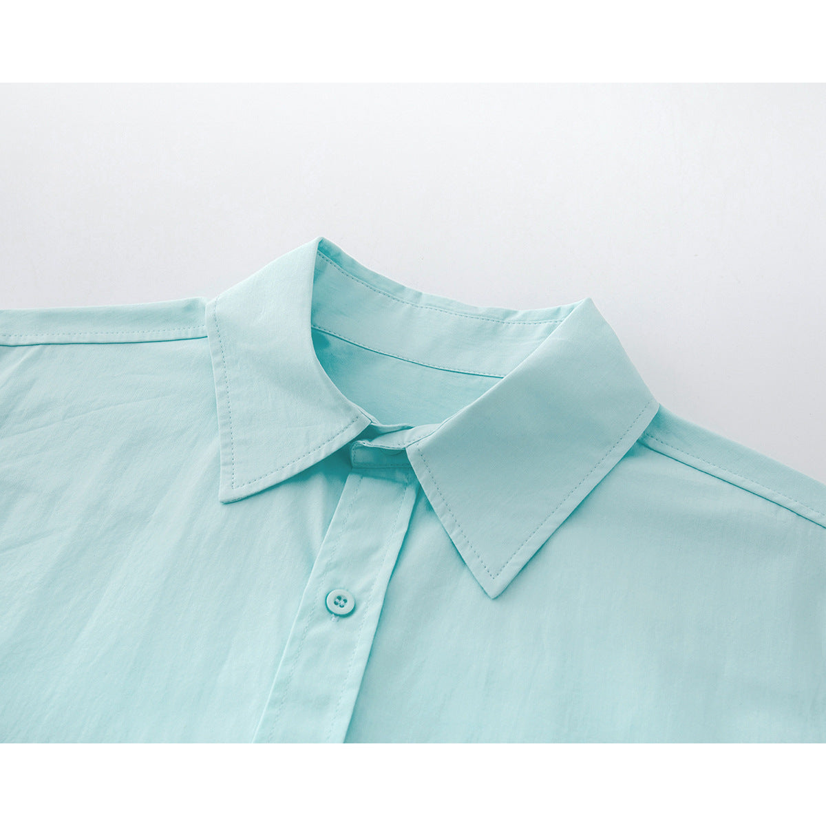 Close-up of a pale aqua button-up shirt collar, top button, and front placket.