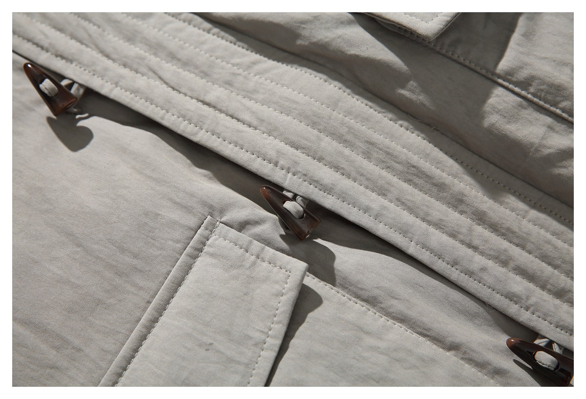 Close-up of the taupe jacket placket with dark toggle fasteners and stitched seams.