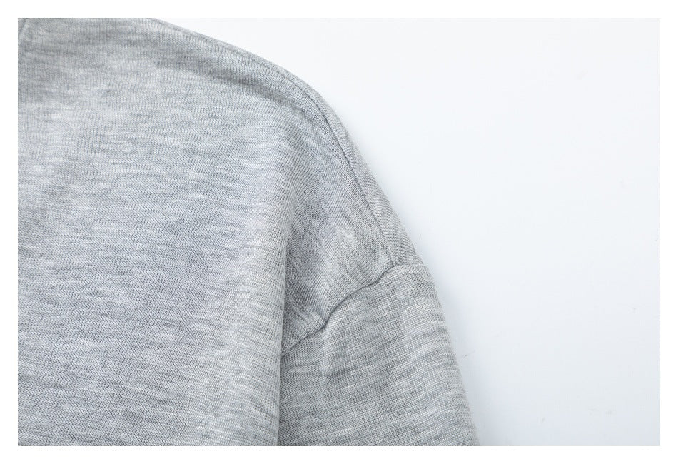 Close-up of a light gray heather knit garment sleeve and shoulder seam.
