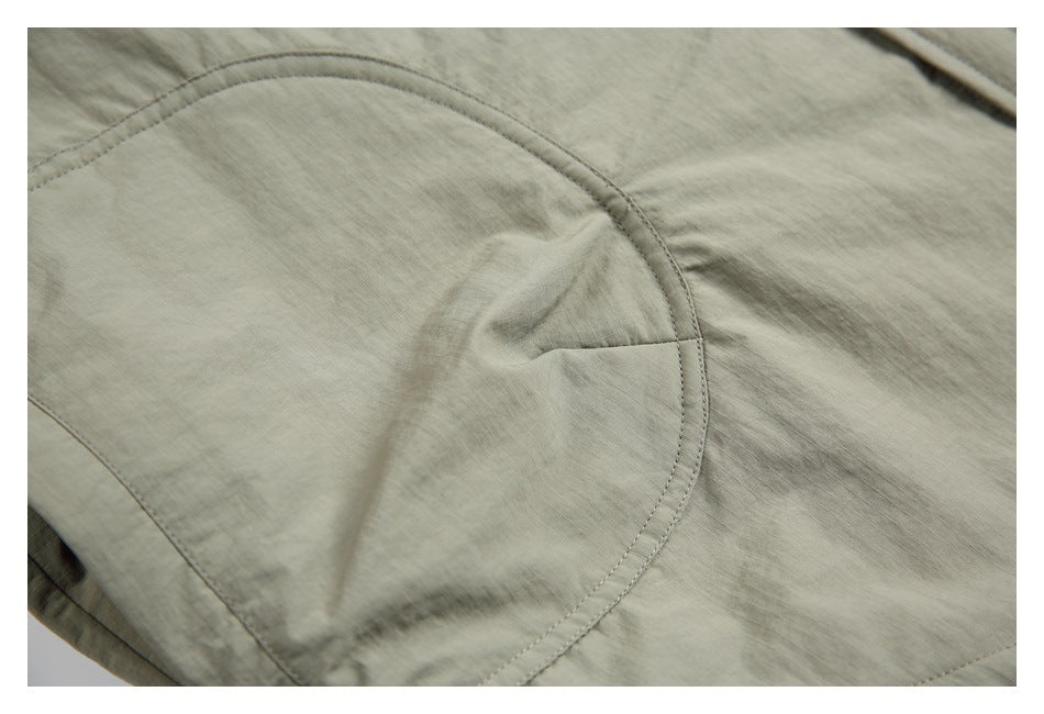 Close-up of a curved double-stitched seam on sage-gray shirt fabric.