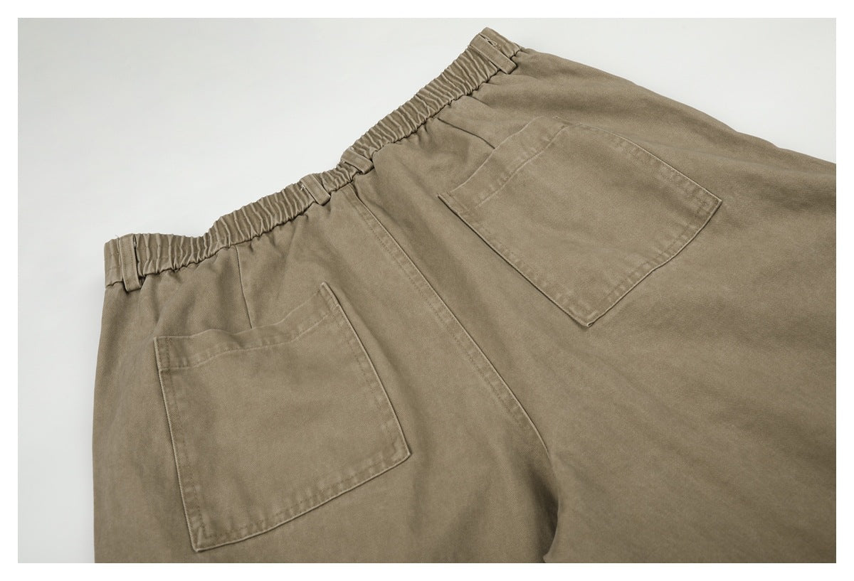 Close-up of taupe-brown trousers showing an elastic waistband and two large patch pockets.