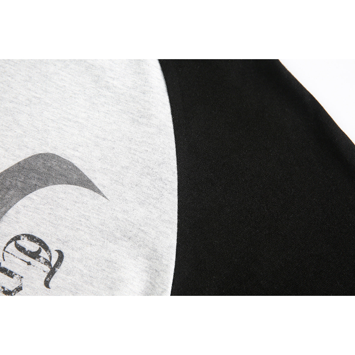 Close-up showing heather-gray shirt fabric, a black color-block panel, and part of a dark printed graphic.