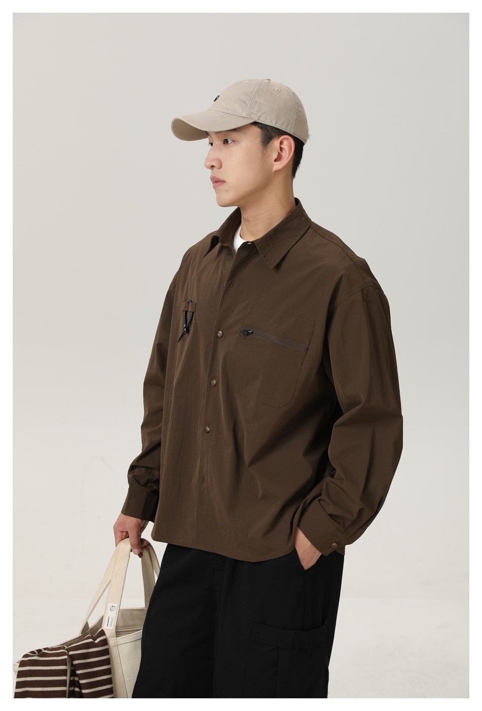 Close three-quarter view of a model wearing a dark brown button-front shirt with a zip chest pocket and cord detail.