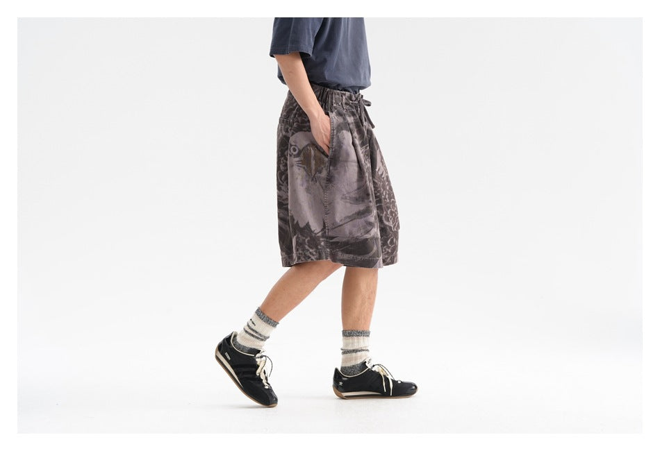 Side view of a model wearing dark gray abstract-print shorts with a drawstring elastic waist and a side pocket.