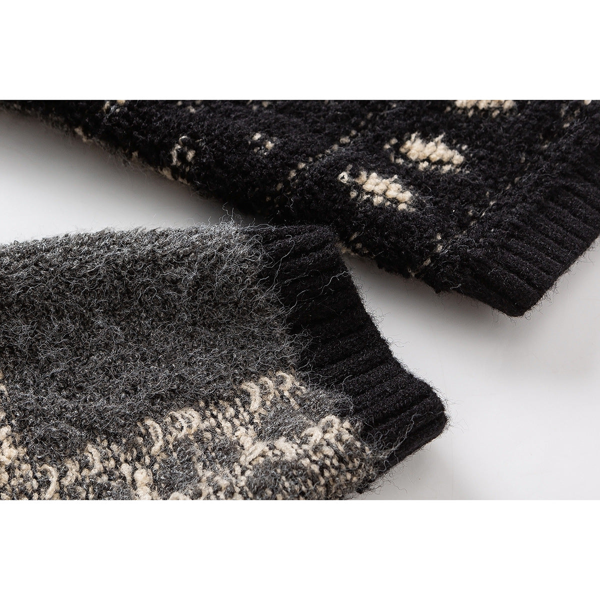 Close-up of ribbed black sweater cuffs beside gray and cream patterned knit fabric.