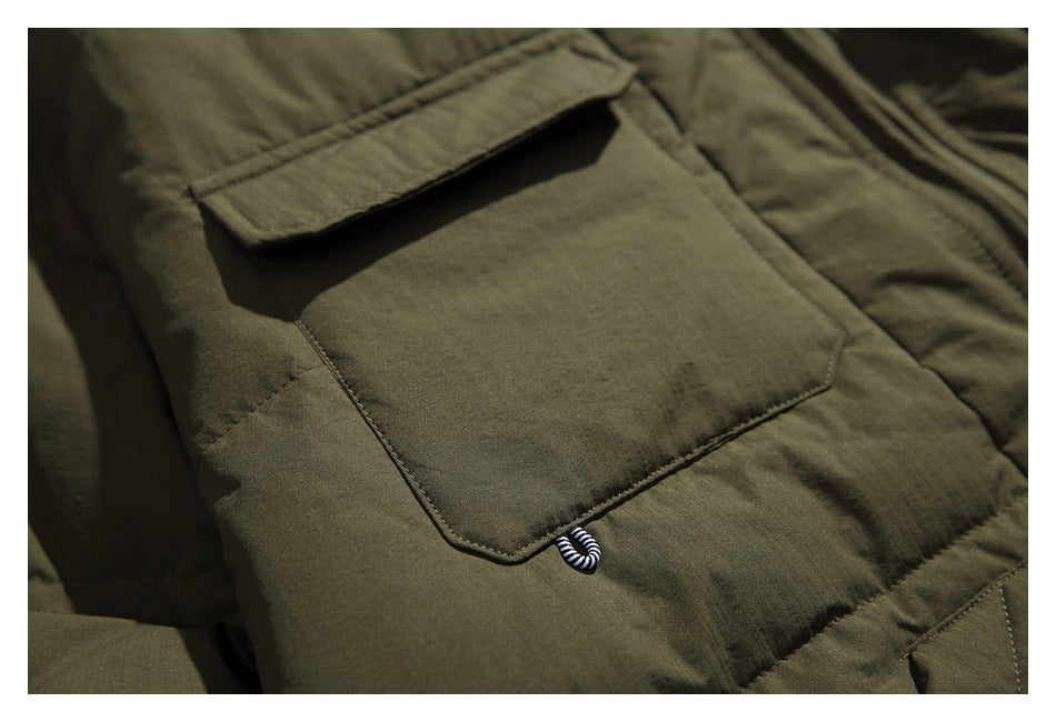 Close-up of a plain flap pocket on an olive green jacket, with a small striped loop below it.