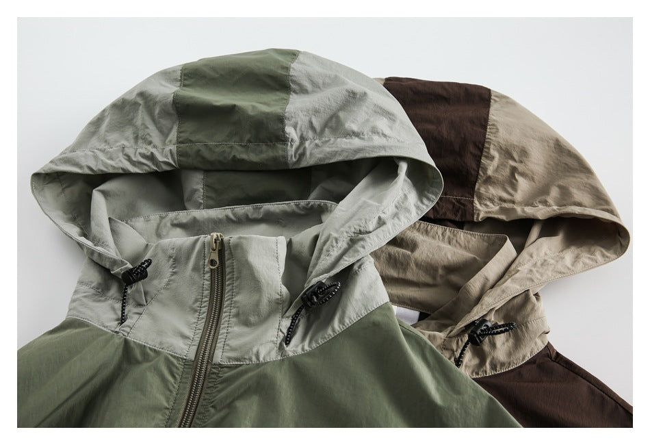 Close-up of two color-block hooded jackets in sage green and taupe, showing the hoods, drawcords and front zippers.