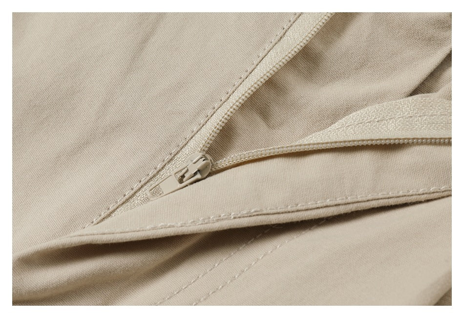 Close-up of a beige garment zipper and stitched seam, with the zipper partially open.