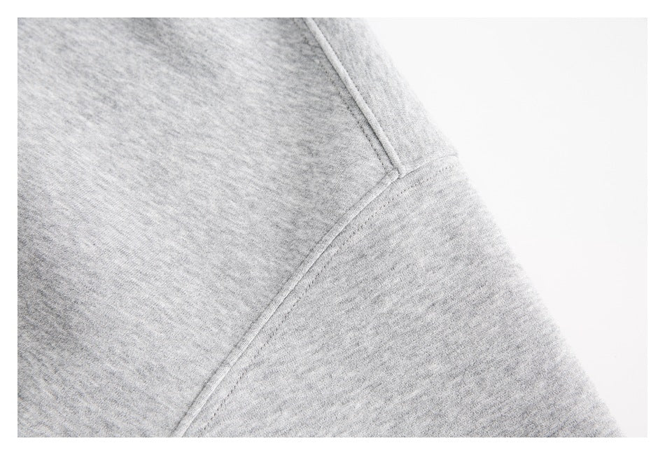 Close-up of a light gray hoodie showing a stitched seam across the fabric.