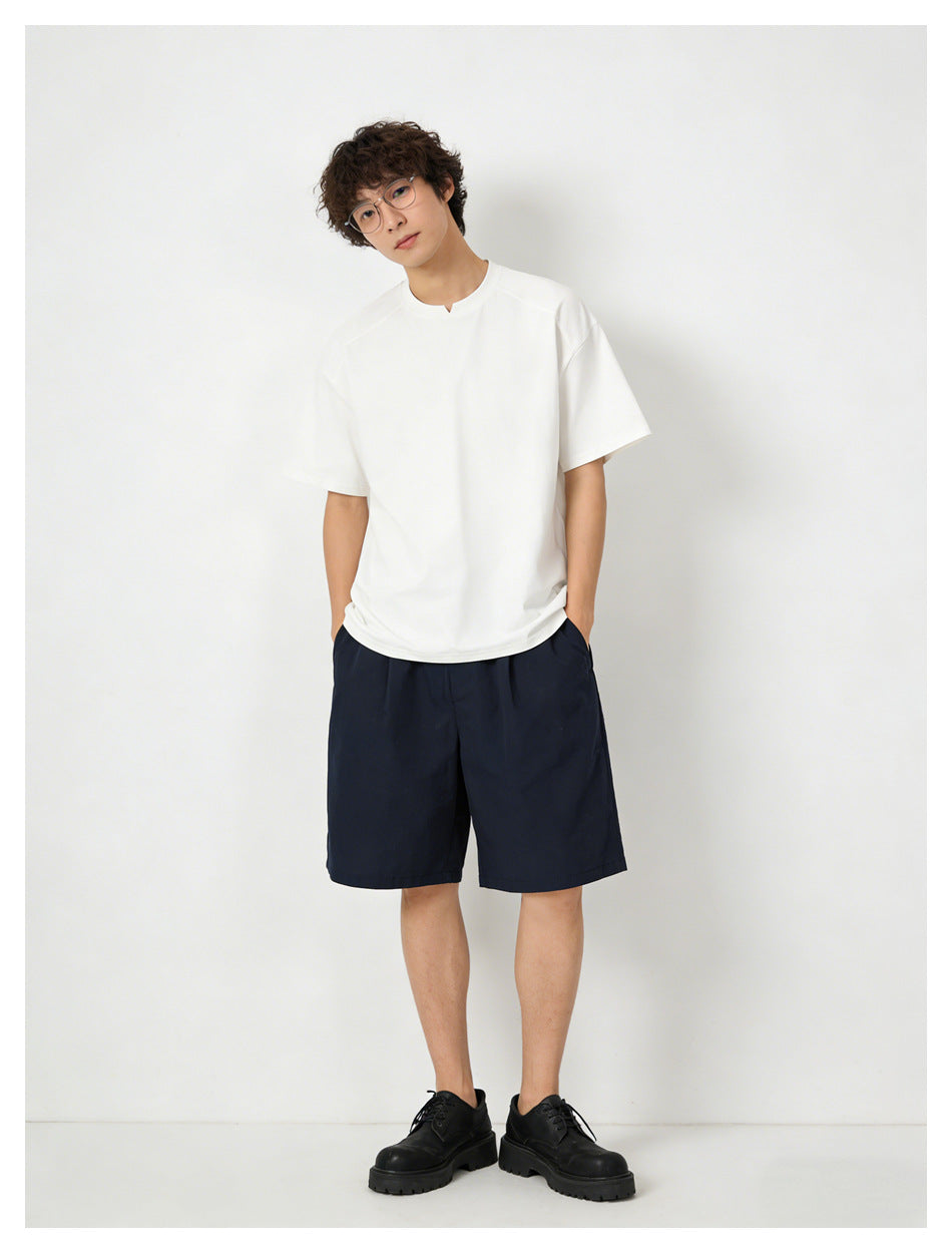 Full-length model wearing a plain white short-sleeve T-shirt with a small center neckline notch and navy shorts.