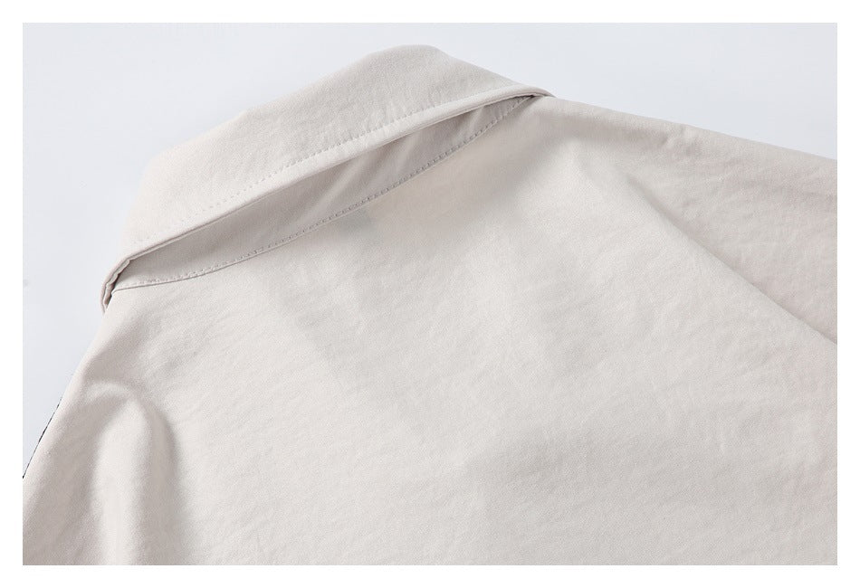 Close-up of the pointed collar and shoulder seam of a pale beige garment.