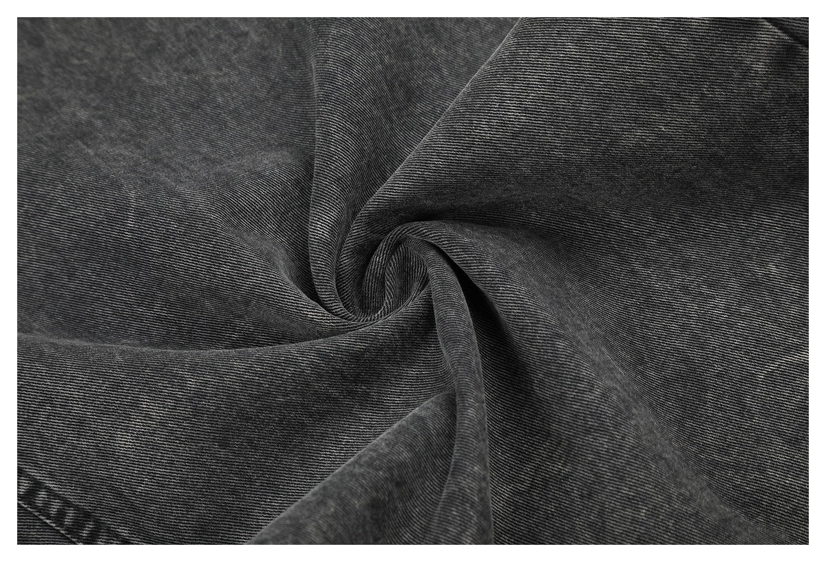 Close-up of the charcoal-gray denim surface, showing its fine diagonal weave and washed texture.