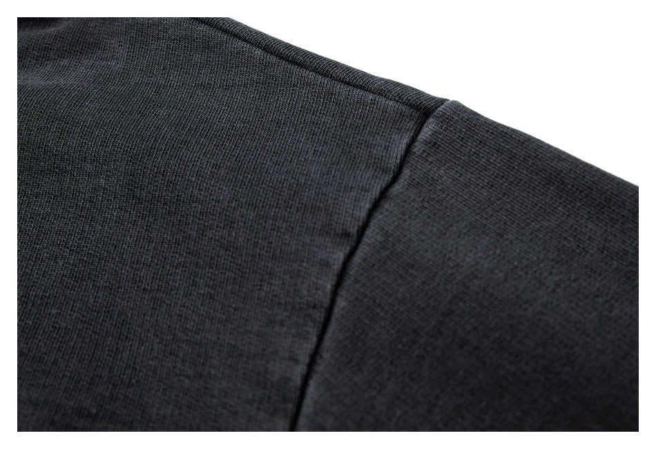 Close-up of charcoal knit fabric and a curved shoulder seam.