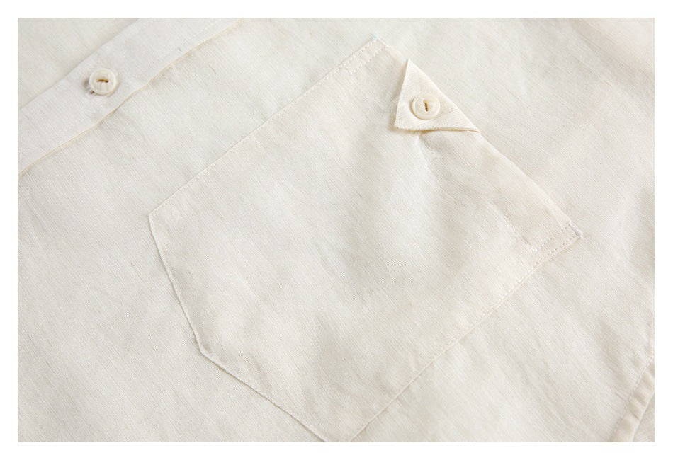 Close-up of an ivory shirt's chest pocket with a buttoned flap.
