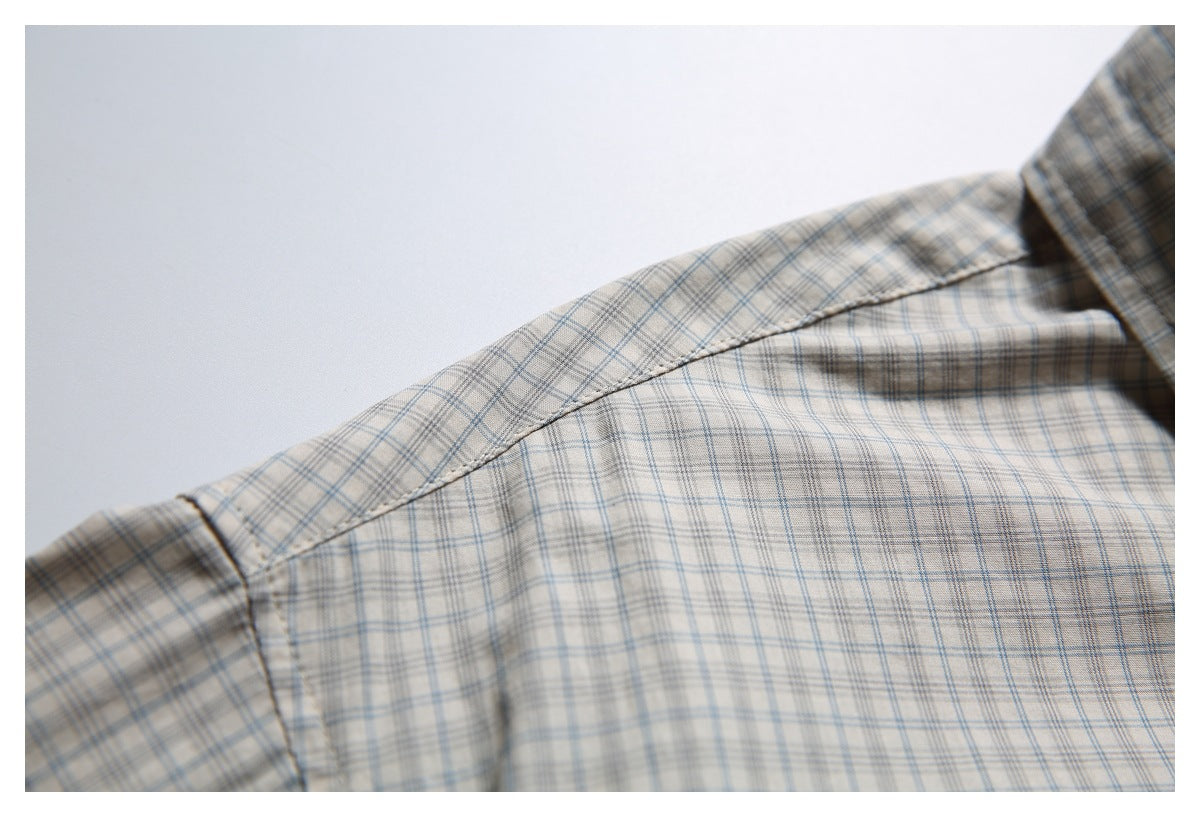 Close-up of the shoulder seam on a beige plaid shirt.