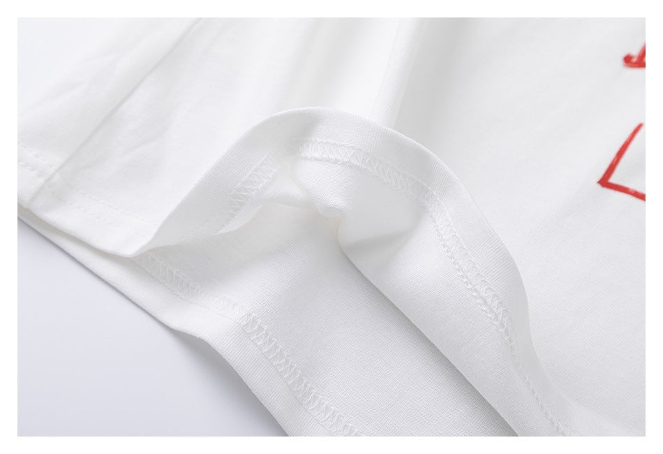 Close-up of the white T-shirt's folded fabric and overlocked seam, with a partial red print at the edge.