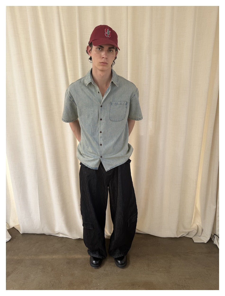 Front view of a model wearing a pale washed-blue short-sleeve button-up shirt with a chest pocket.