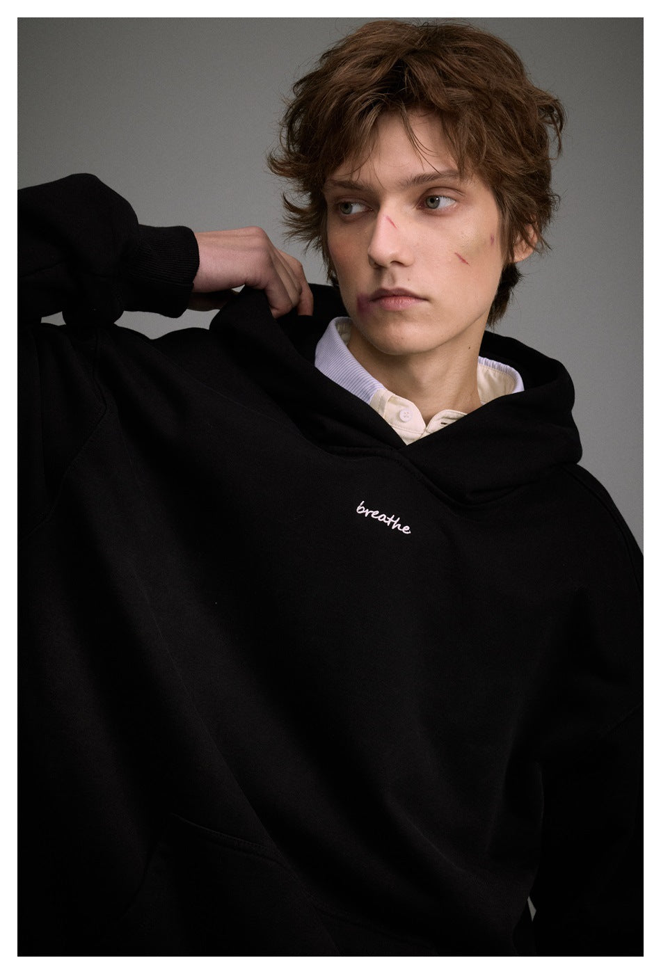 Close view of a model wearing a black hoodie with small white “breathe” script on the chest.