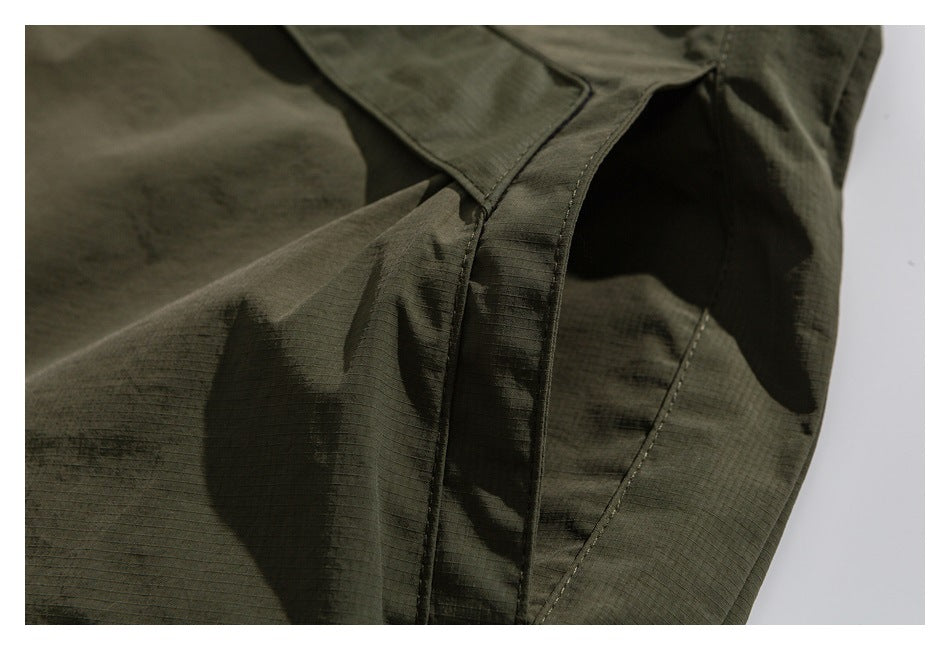Close-up of olive garment fabric showing a stitched seam and overlapping panel.