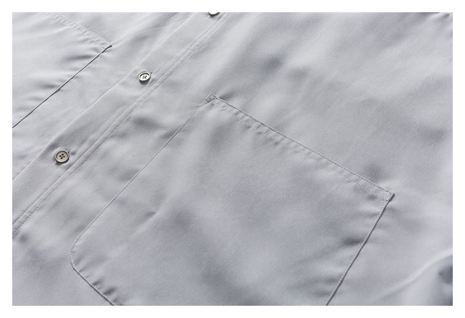 Close-up of the light gray shirt's button placket and large stitched chest pocket.