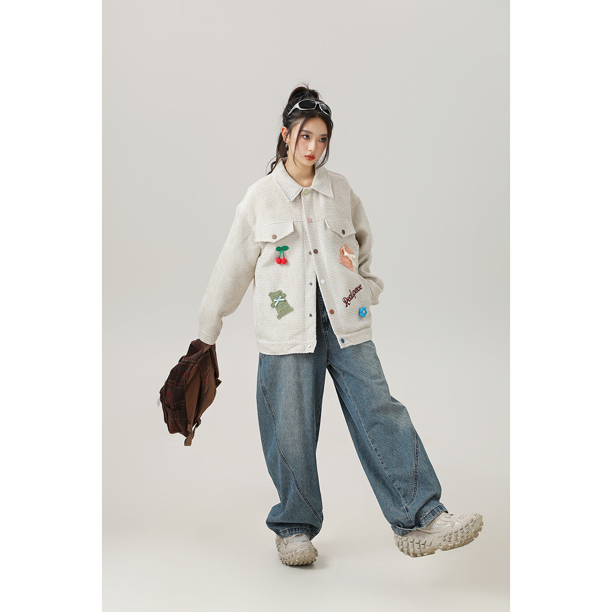 Model wearing a cream embroidered button-front jacket with blue wide-leg jeans, shown from the front.